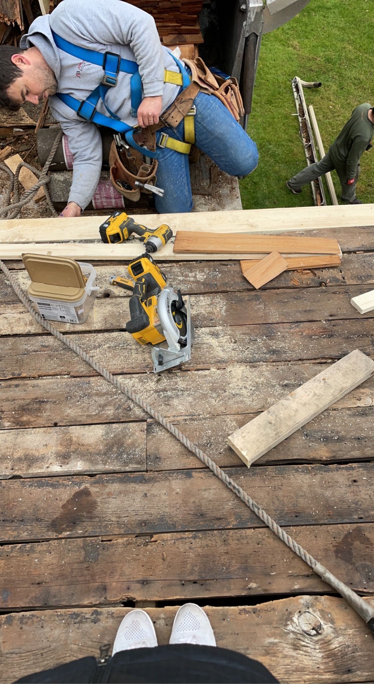 Two-story white house with brown roof and a tall brick chimney, trees in the background under a blue sky.