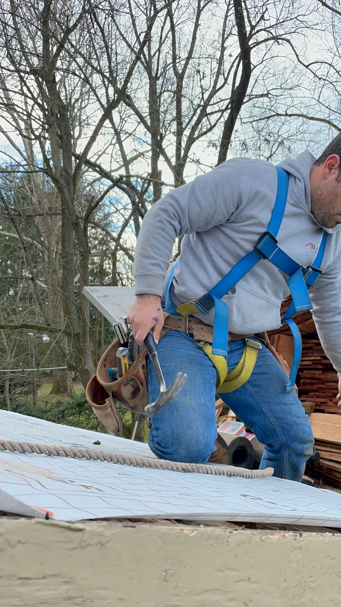 Damaged asphalt shingles on a roof, revealing wood sheathing and debris.