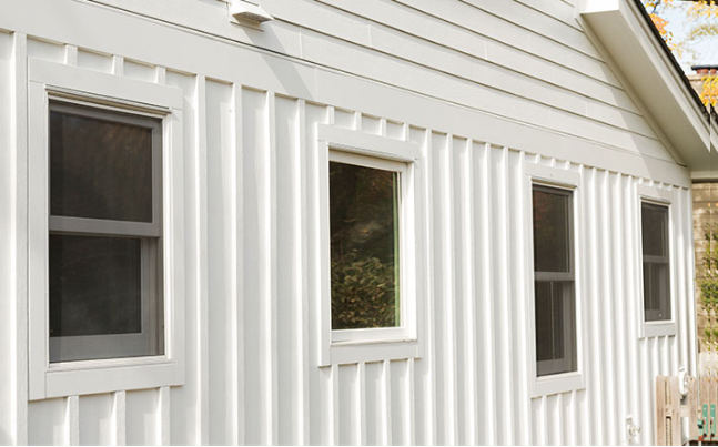 Two-story brick house with gray tiled roof and climbing ivy.