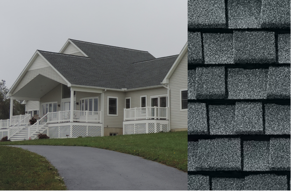 House with a dark gray shingle roof and a section of roofing shingles. A driveway leads to the house.