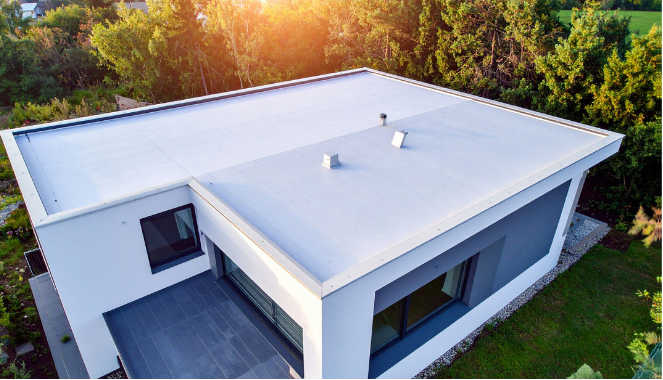 Modern house with flat white roof and dark accent wall, aerial view.