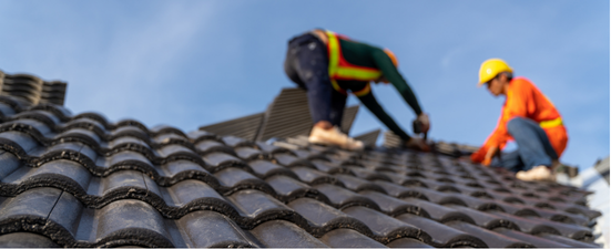 Construction workers installing roof tiles on a house.