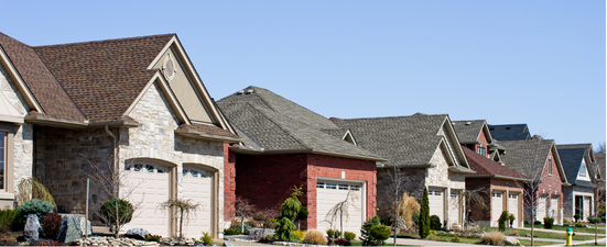 Row of houses with various colored brick and stone exteriors under a clear blue sky.