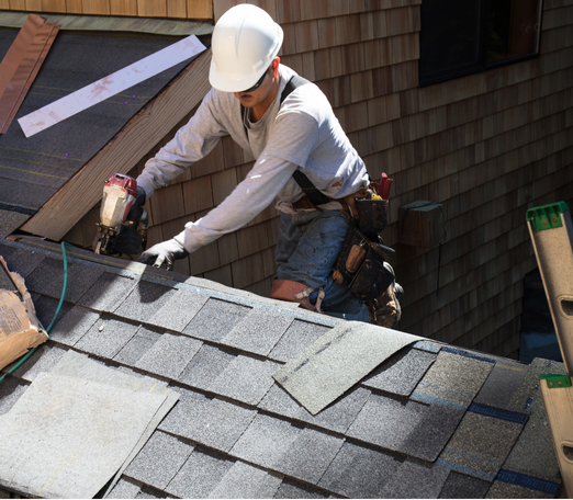 Roofer hammering on a roof, wearing a tool belt. Sunlight casts shadows.