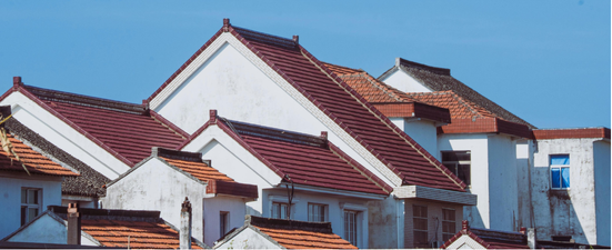 Buildings with white walls and red tile roofs against a blue sky.