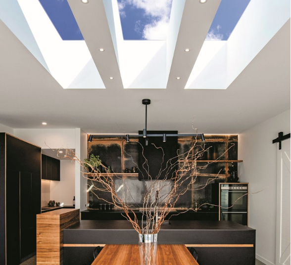 Kitchen interior with skylights. Black cabinets, wooden countertop, and branches in a vase.