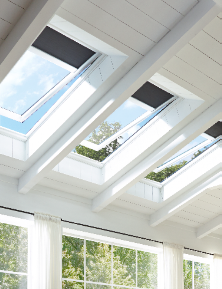 White ceiling with three open skylights, black blinds, visible sky and trees.