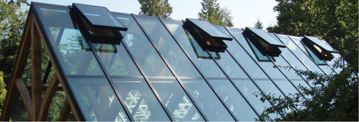 Glass roof with open vents in a garden setting.