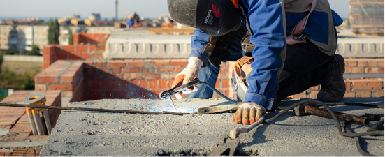 A house being worked on with a partially replaced roof. Green trees surround the house.