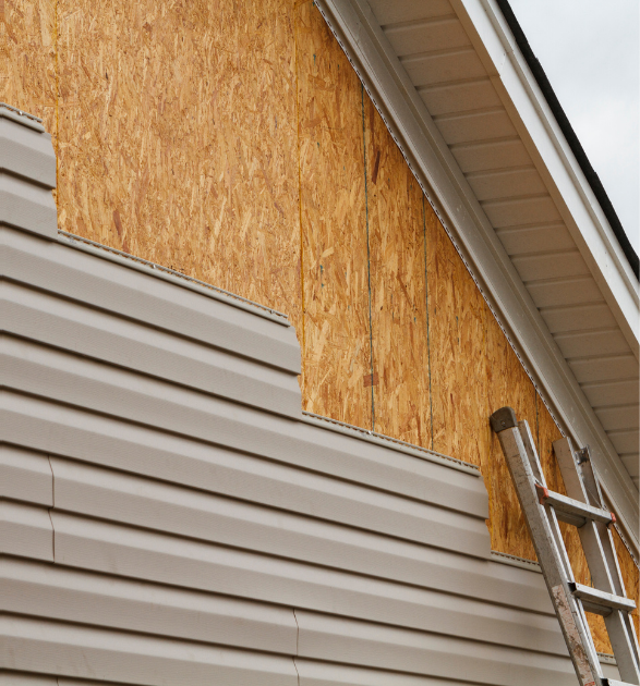 House siding partially removed, revealing plywood. A-frame roofline with ladder.
