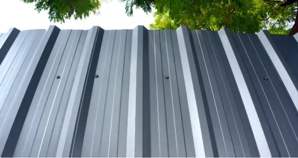 Gray shingled roof of a house with a turret and curved architectural elements. Sunny day.