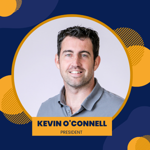 Kevin O'Connell, smiling, in a gray polo shirt, against a gradient background with yellow and blue shapes. 