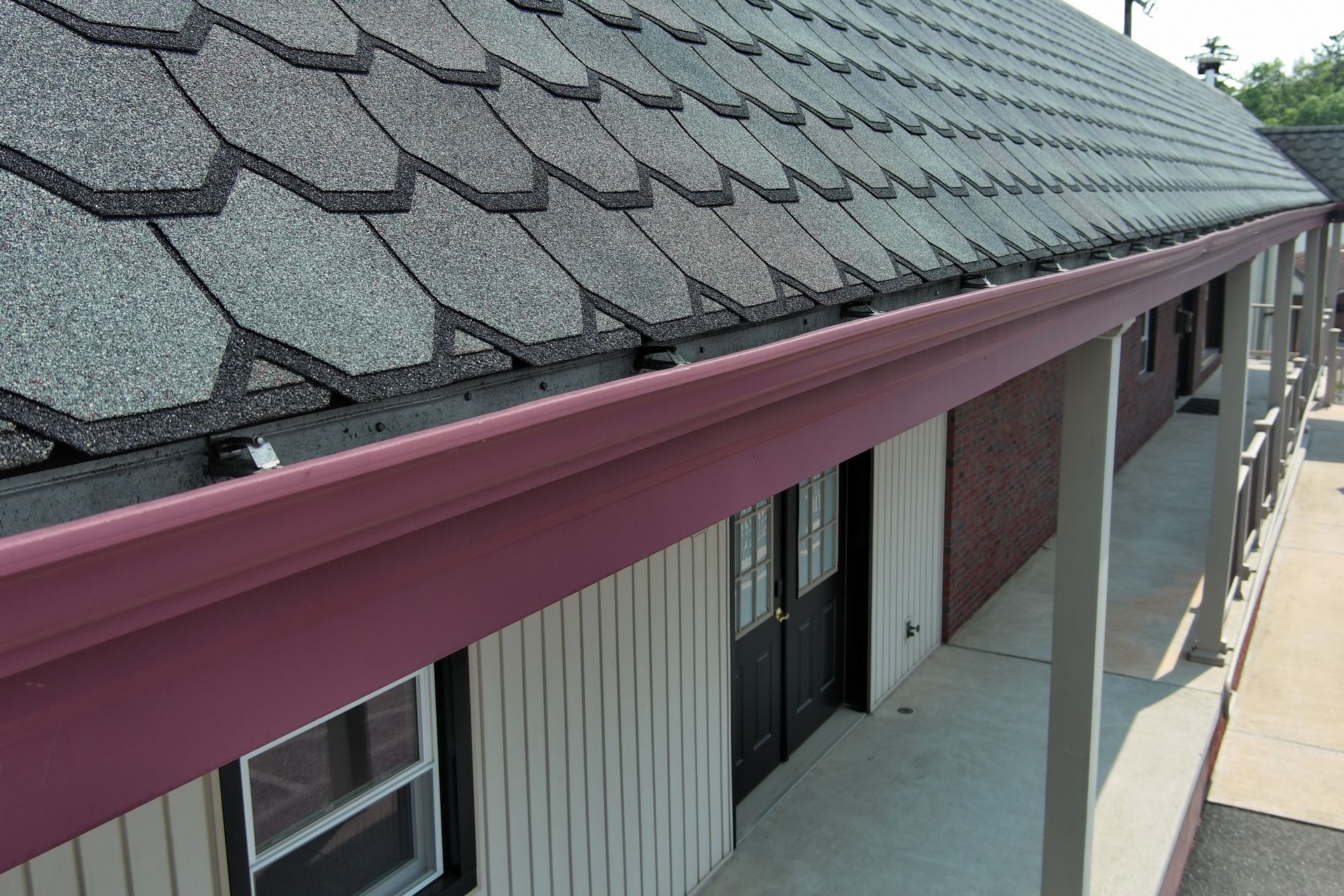 Wooden shingle roof with copper flashing along the angled edge. Beige gutter below.