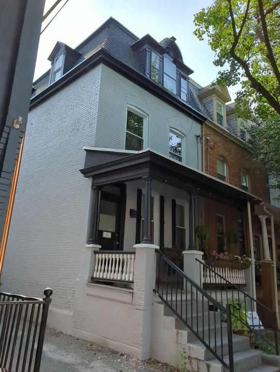 Row of townhouses, the first is light blue with a porch. Stairs lead up to the porch.
