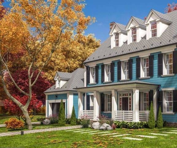 Two-story blue house with white trim, porch, and dormers, set in a yard with fall foliage.