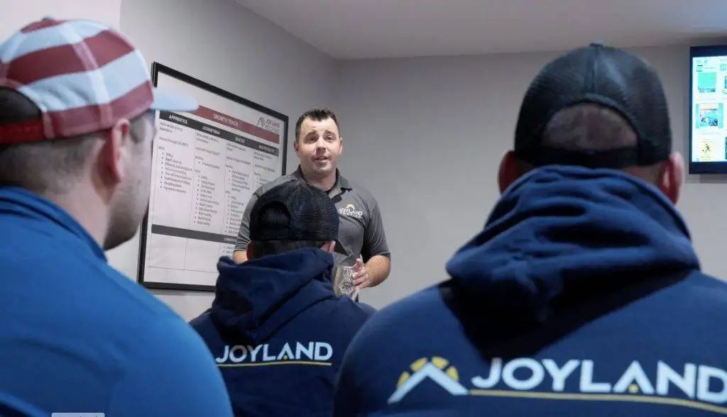 Man speaking to a group of people wearing blue Joyland sweatshirts.