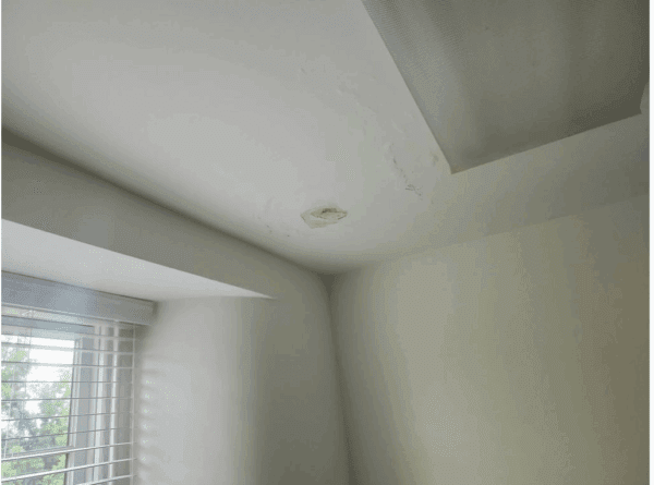 Room with a white ceiling and walls, a window with blinds, and a light fixture.