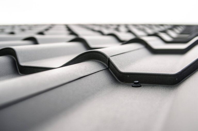 Close-up of a black metal roof with overlapping, curved tiles.