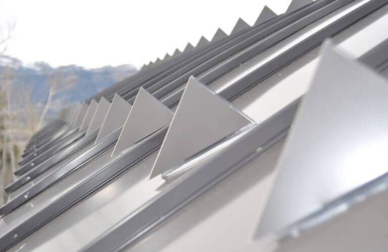 Close-up of a metal roof with triangular, sawtooth-shaped vents along the edge.