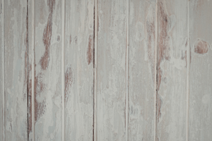 White ceiling with peeling paint in the corner of a bathroom with gray honeycomb tile.