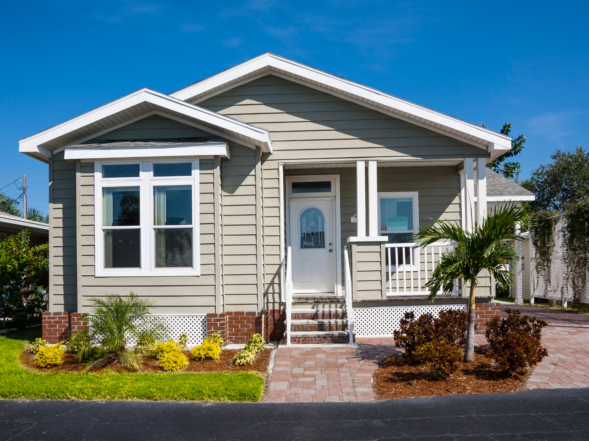 Two-story house with brick, stone, and tan siding; dark gray shingled roof, porch, and windows.