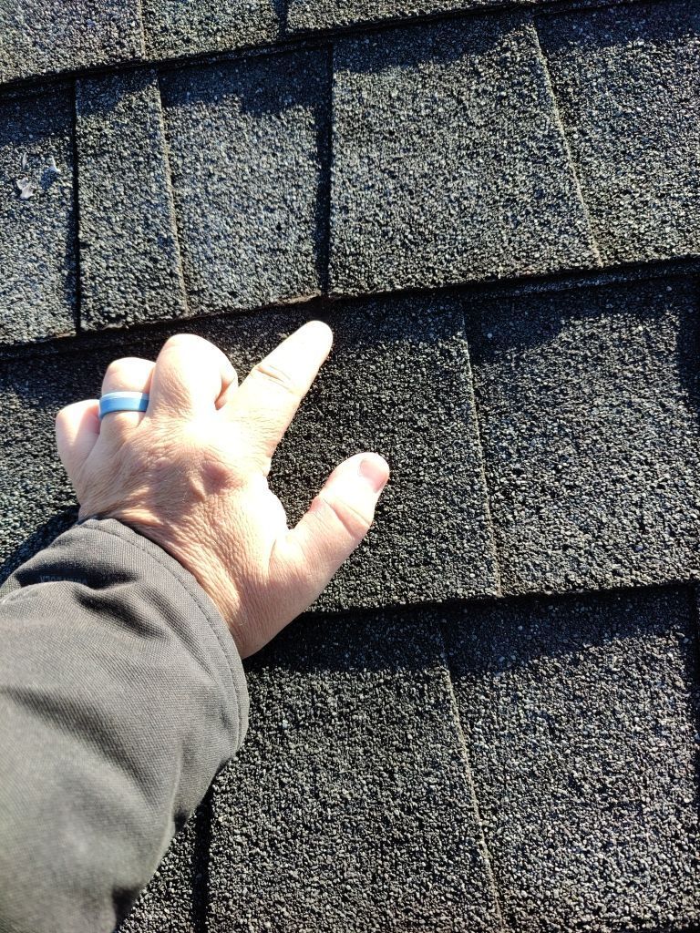 Roofing professional checking the condition and seal of asphalt shingles during a roof inspection on Jonestown Road in Jonestown, PA.
