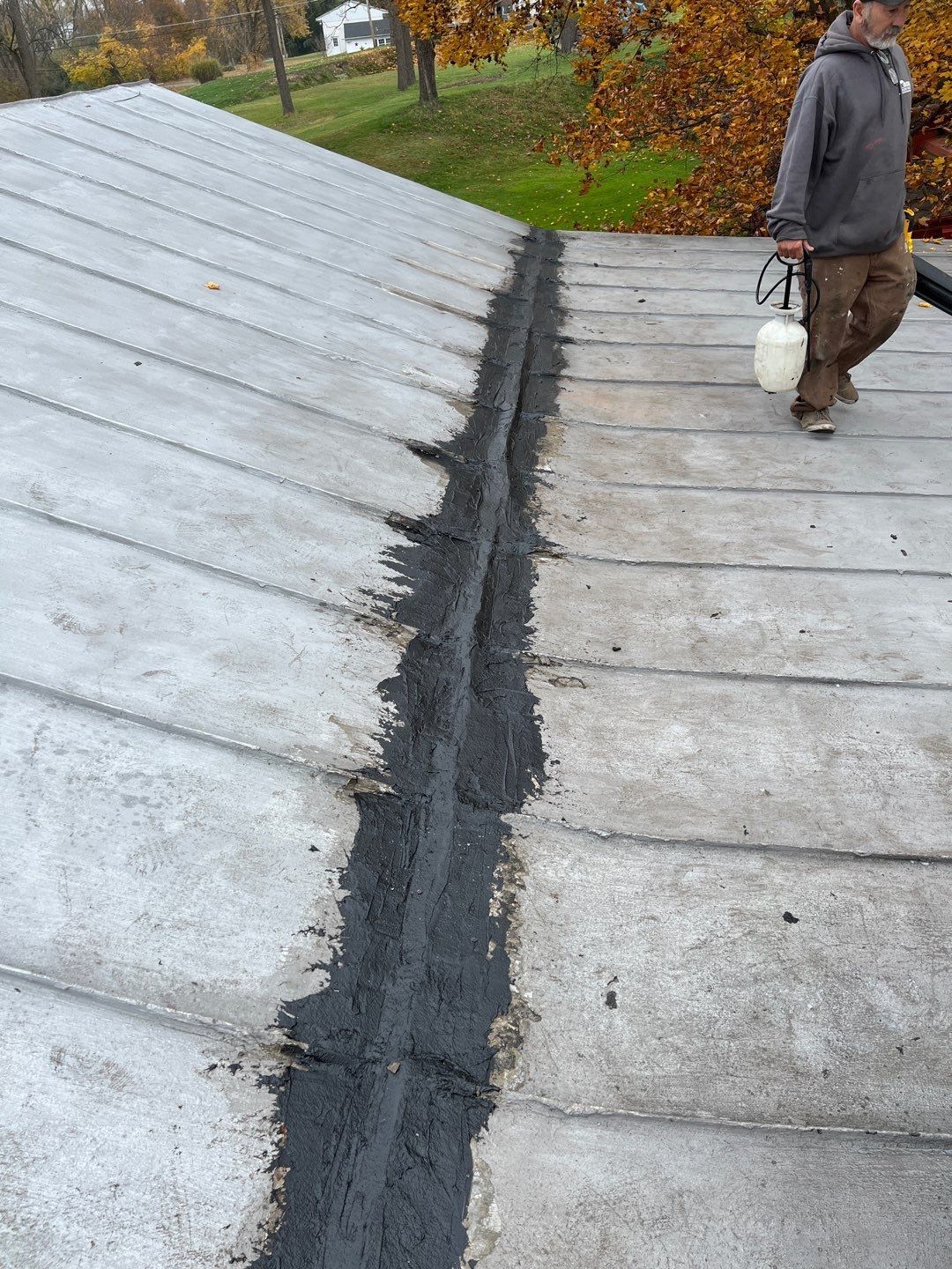 Technician reinforcing a flat roof seam with roofing sealant during a roof repair project on Lickdale Road in Jonestown, PA.
