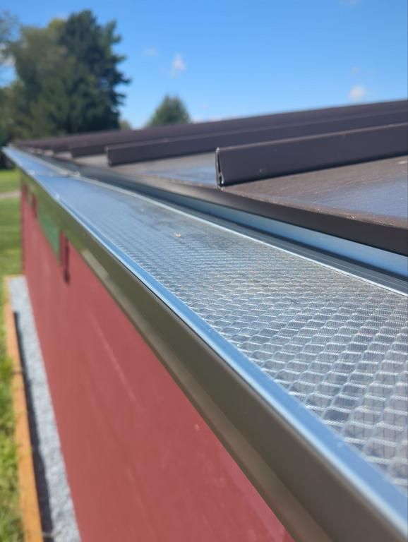 House with attached garage, covered porch, and asphalt driveway on a grassy hill under a cloudy sky.