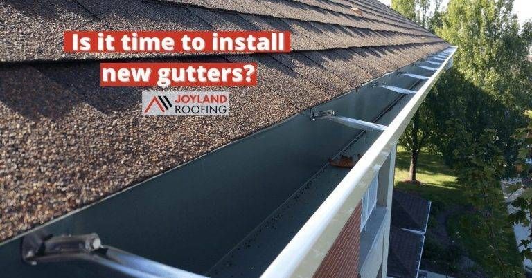 A gutter on a brown shingled roof with text asking if it's time to install new gutters. 