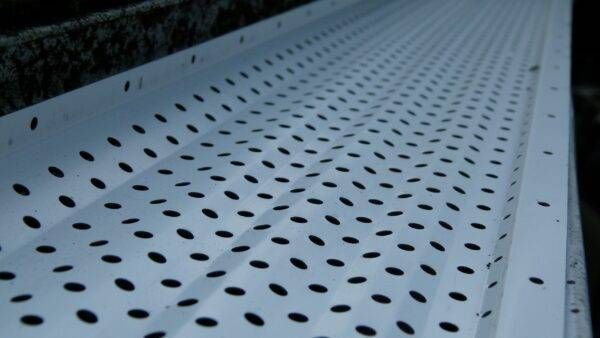 White perforated gutter guard with oval holes.