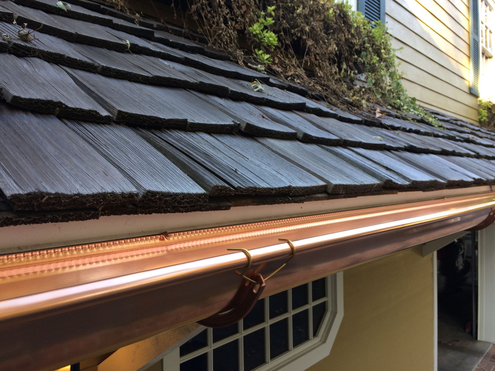 Wooden shake roof with copper flashing, close-up view.