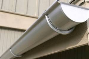 Gray seamless rain gutter attached to a building's exterior.