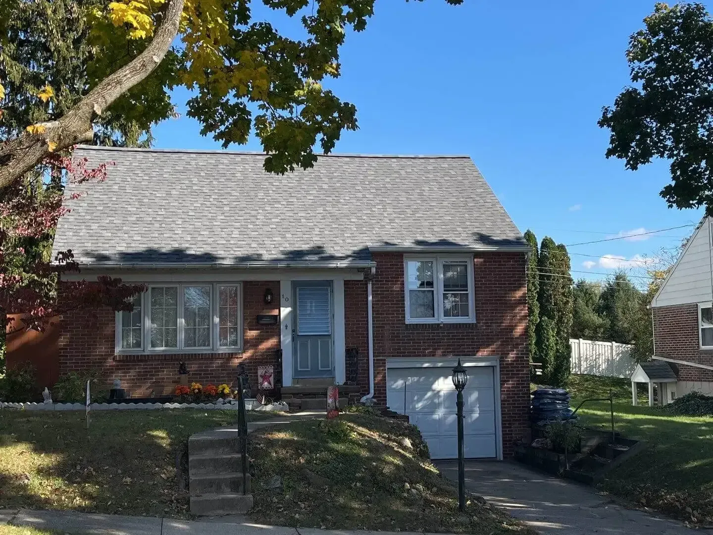 Brick house with a gray roof, small front yard, and a one-car garage.