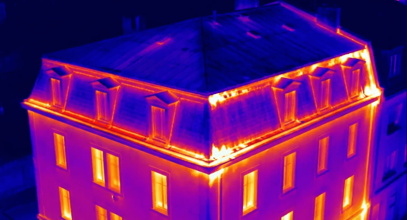 Thermal image showing heat loss patterns around a mansard roof and upper floor envelope