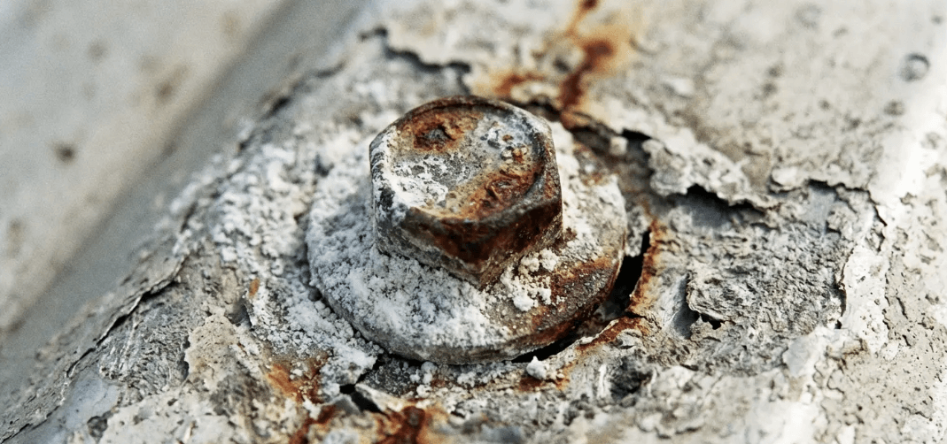 Corroded roof fastener and sealant failure showing risks of improper snow guards installation over time