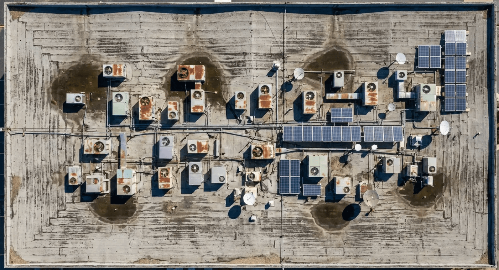 Commercial roof deck crowded with HVAC units and solar panels adding structural load.