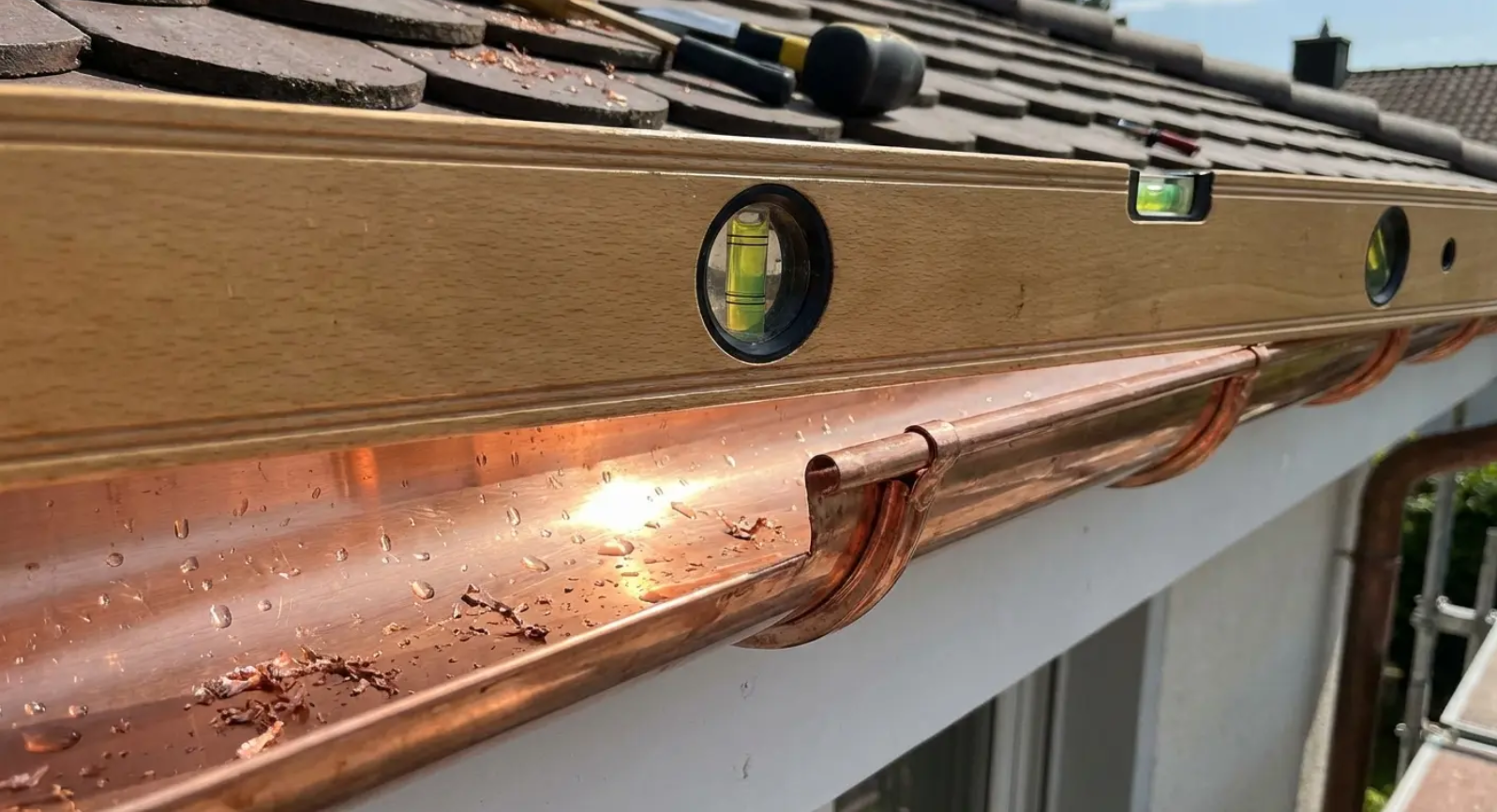 A level placed on new gutters to ensure the correct slope during gutter replacement.