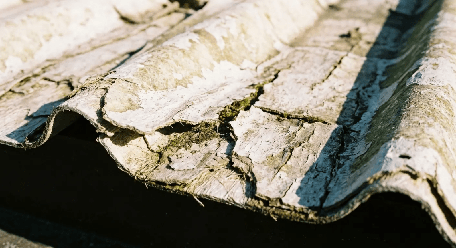Cracked and peeling composite roofing material up close, showing what climate mismatch does to budget patio roof ideas over time