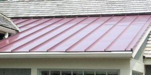 Red metal roof on a light-colored building with white trim.