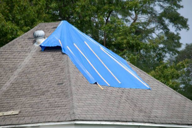 Blue tarp covering a portion of a brown shingled roof, likely protecting against damage.