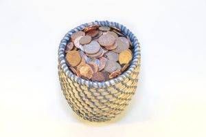 Basket filled with assorted coins, with a woven blue and white rim.