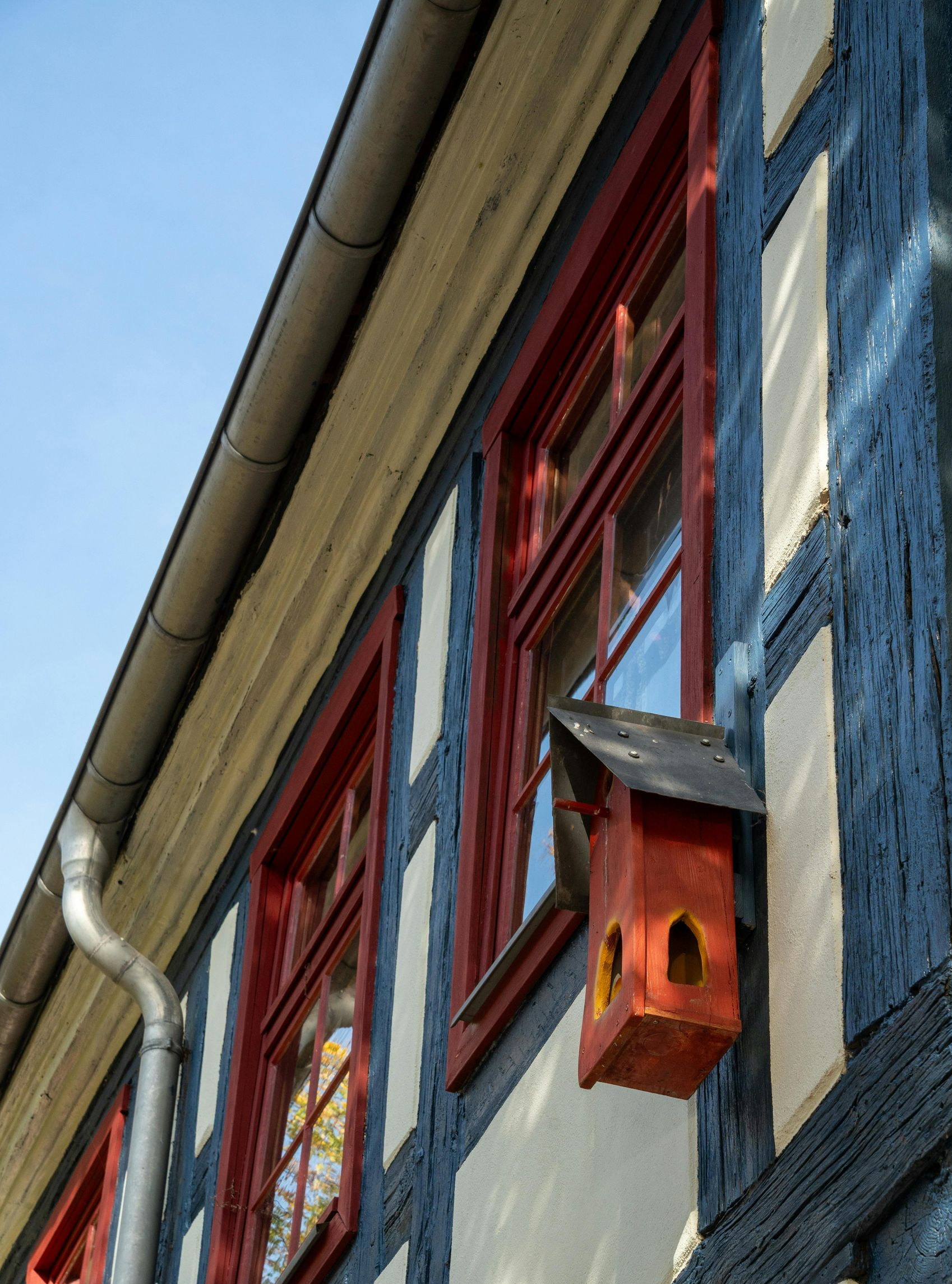 Two-story blue house with shutters and a three-car garage, on a green lawn under a blue sky.