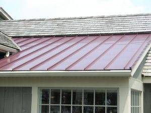 Red metal roof on a house, contrasting with a gray shake roof.