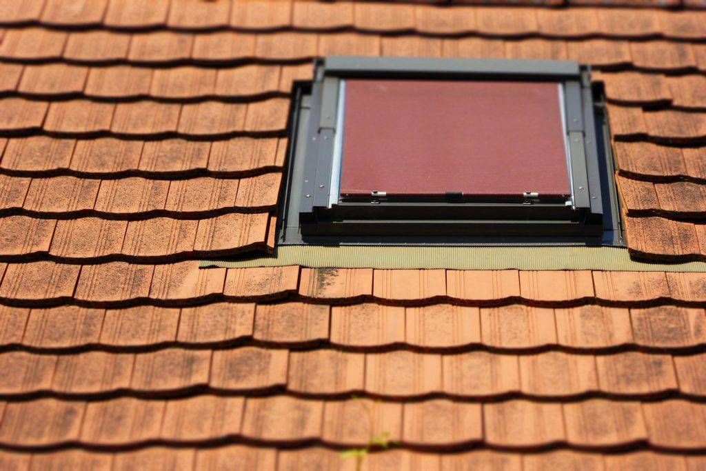 Skylight on a brown shingle roof, with a burgundy shade drawn.