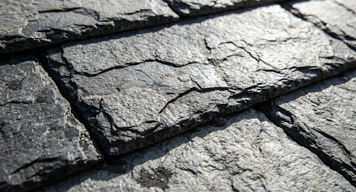 Close-up of gray slate roof tiles, overlapping in rows, textured and weathered.