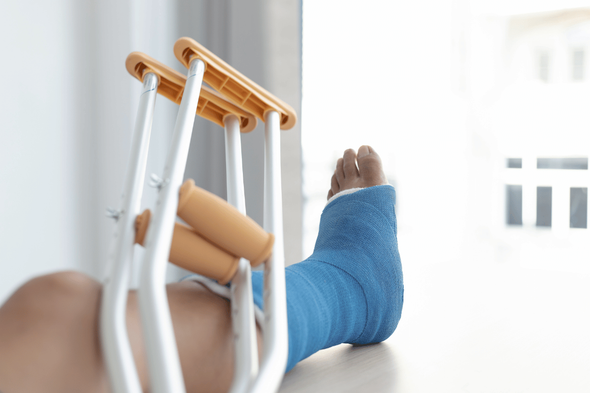 A person with a cast on their leg is laying on a table with crutches.
