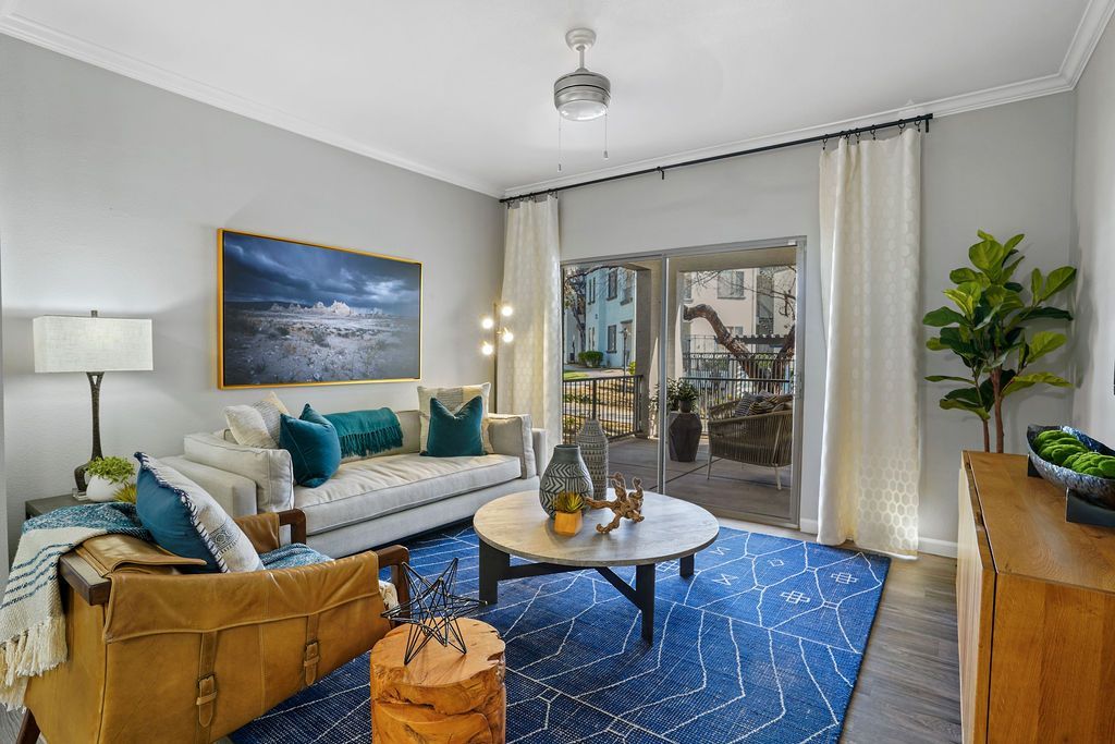 Living room with beige sofa, blue geometric rug, and sliding glass door to a balcony.