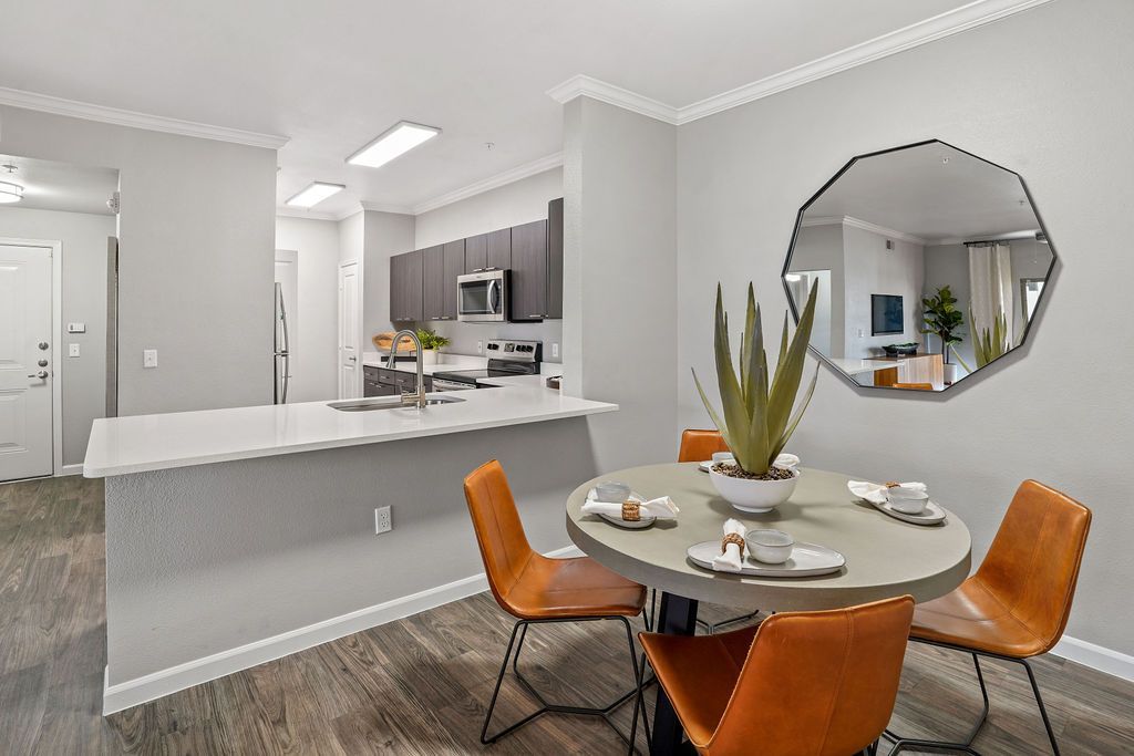 Open-concept kitchen and dining area in a modern apartment with an island and round table.