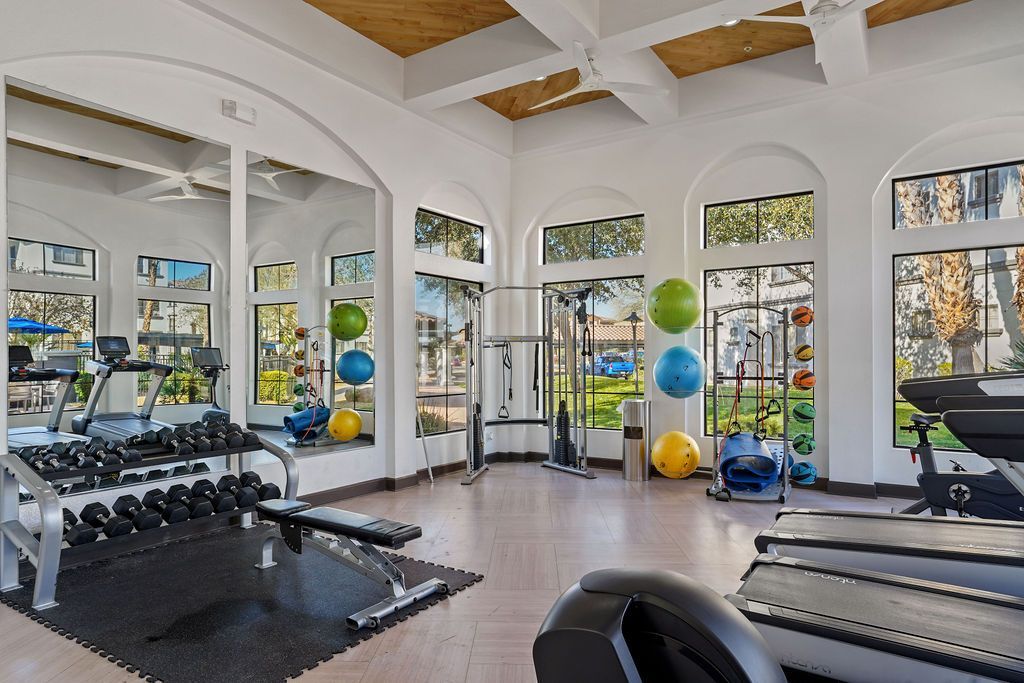 Bright fitness center with treadmills, weights, and colorful exercise balls.