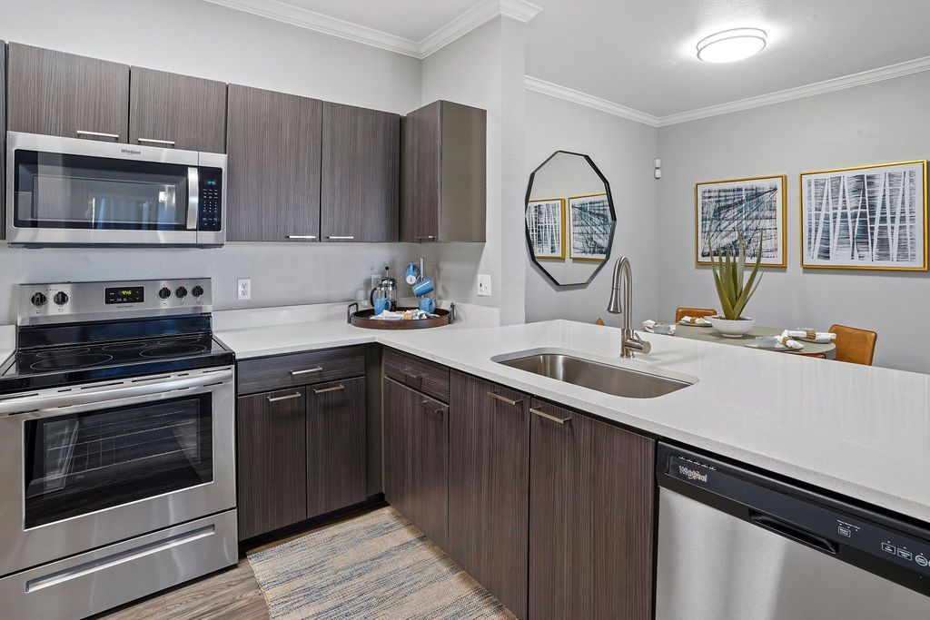 Modern kitchen with stainless steel appliances, dark wood cabinets, and a white island.